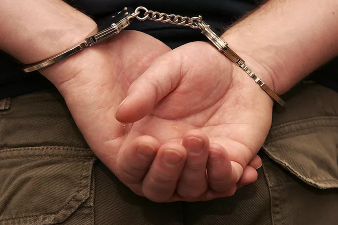 Image of man with hands handcuffed behind him after possible sex crime