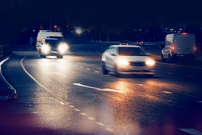 image of vehicles driving at night with their headlights on.